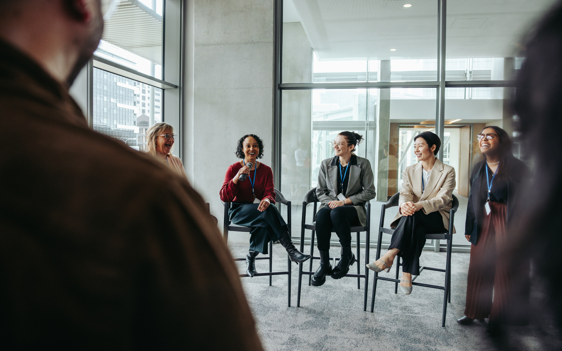 Businesswomen speaking at a conference event. They are engaged in a lively professional discussion, sharing insights and ideas.